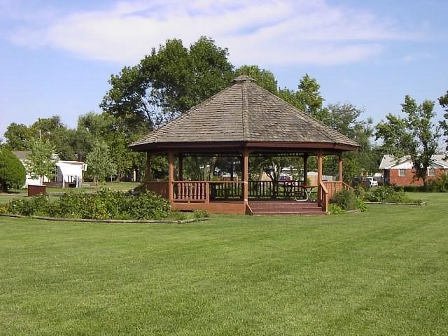 A gazebo surrounded by a lush lawn and trees in a serene park setting